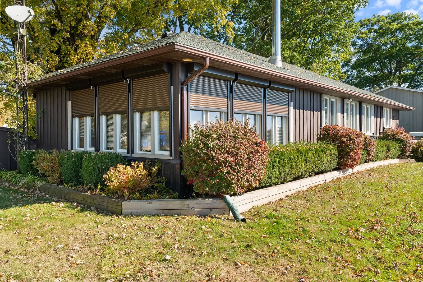 Brown Ontario bungalow with multiple aluminum roll shutters deployed on the lakeside windows