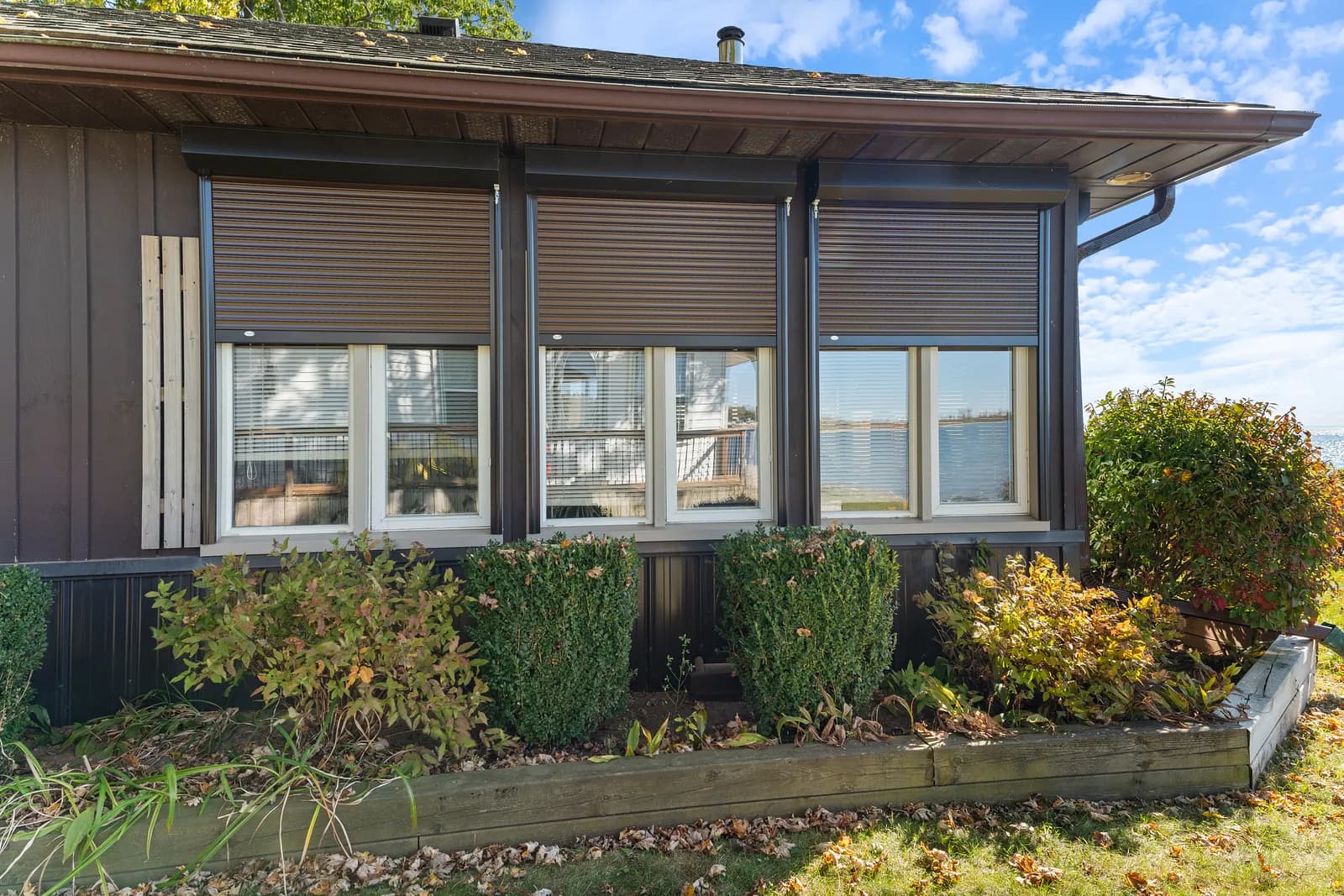 Aluminum roll shutters in mid-deployment on an Ontario cottage ahead of a winter storm