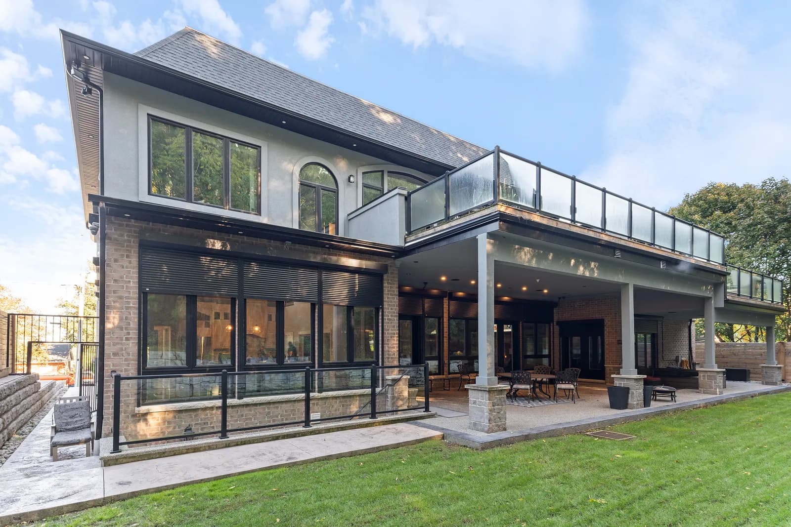 Aerial view of a modern luxury home with aluminum roll shutters retracted across the rear elevation