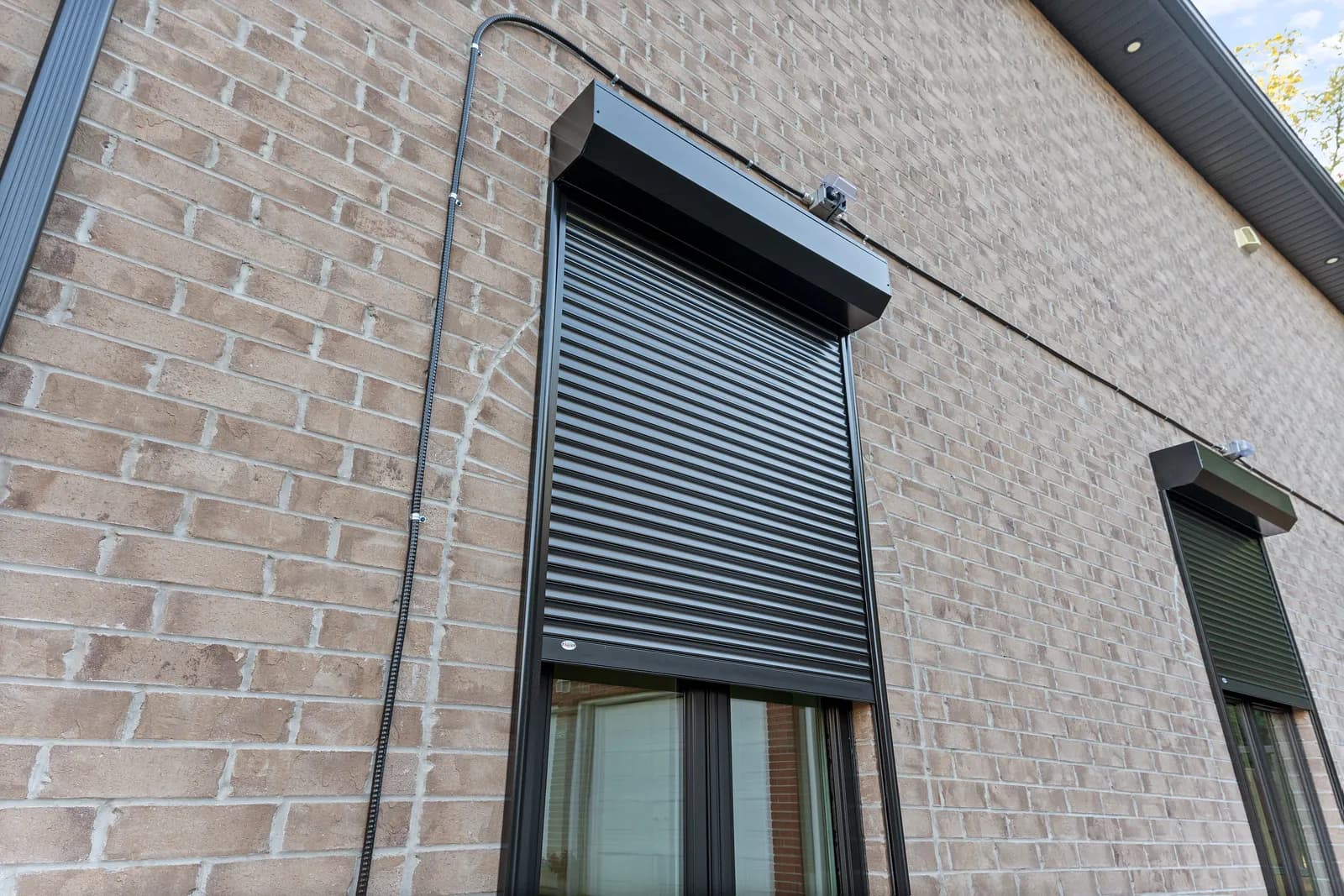 Tall vertical view of a residential home with aluminum roll shutters on the side elevation