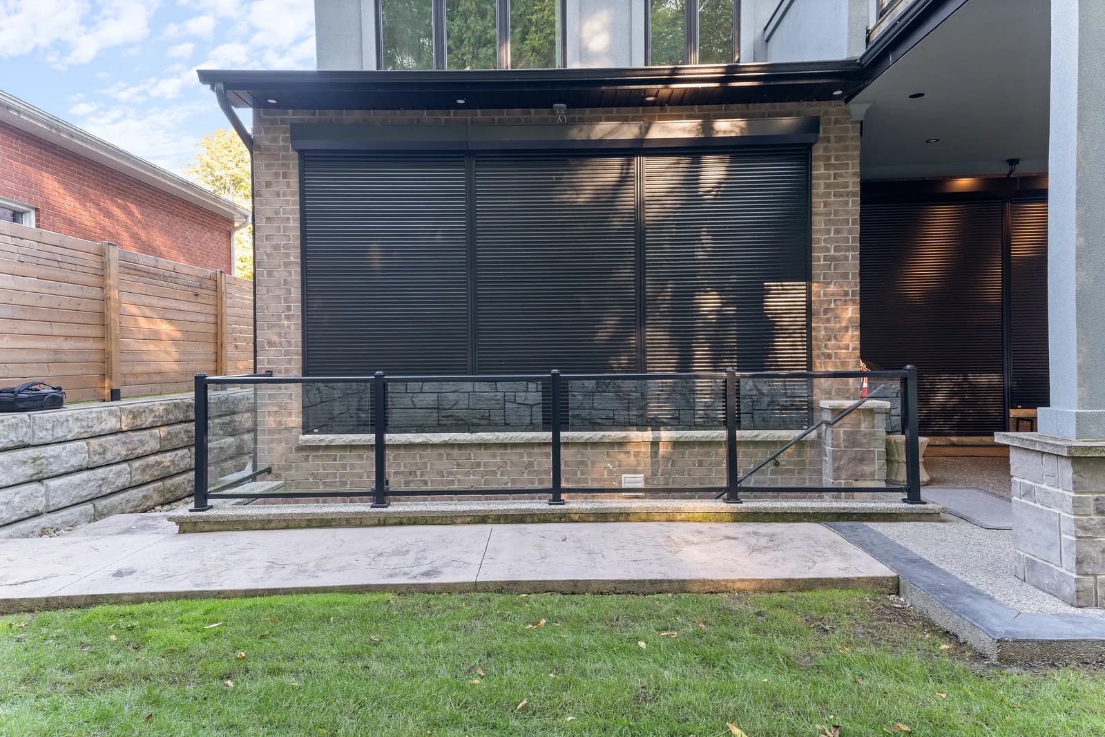 Modern patio with three large black aluminum roll shutters fully deployed across the back wall